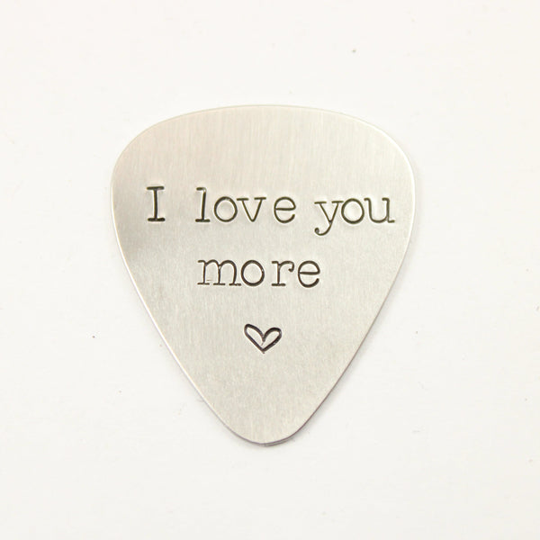 Guitar pick stamped with "I love you more" and a heart 