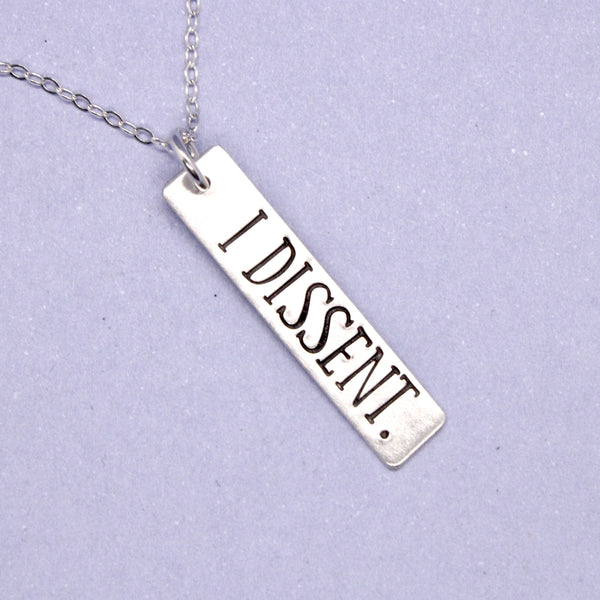 Silver charm stamped with "I dissent" with a silver chain
