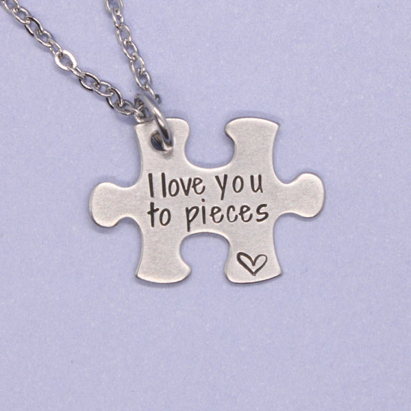 Silver puzzle piece pendant with 'I love you to pieces' text on a purple background