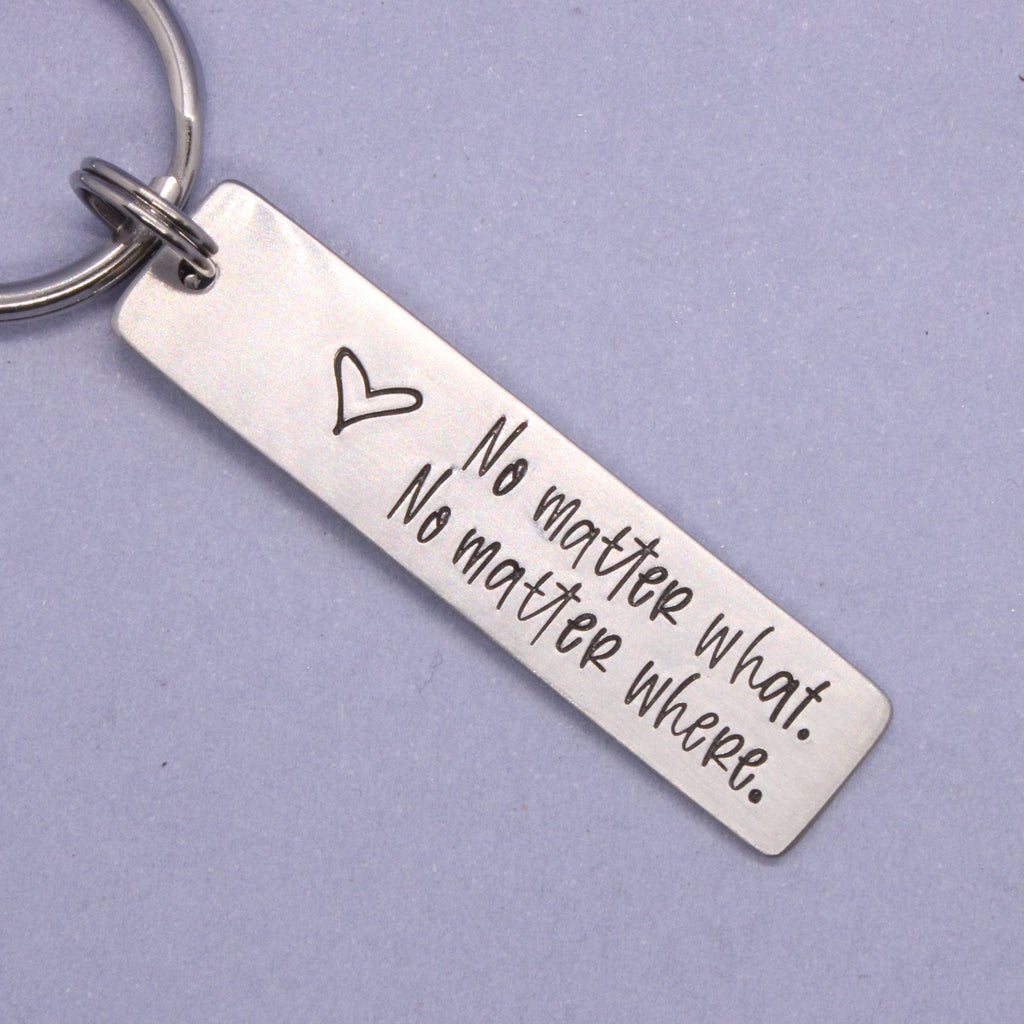 Silver keychain with engraved text on a purple background