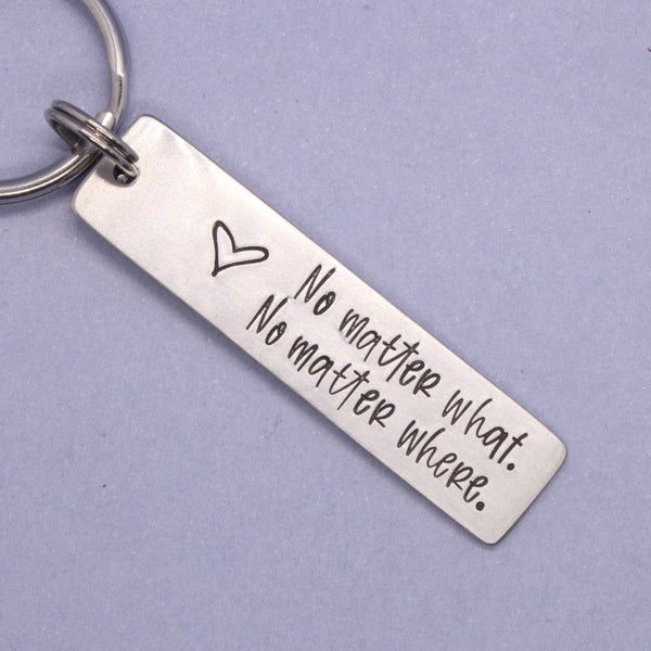 Silver keychain with engraved text on a purple background