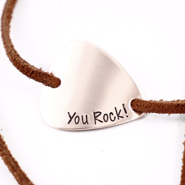 Copper pendant with 'You Rock!' engraving on a brown cord against a white background